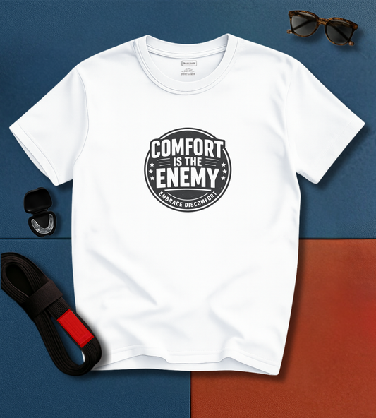 White BJJ t-shirt with 'Comfort is the Enemy' graphic on a blue and brown gradient background